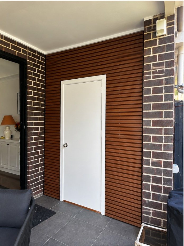 The same alfresco wall clad in timber slats with a new painted door, after